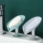 Leaf-shaped self-draining soap holder with suction base on bathroom sink